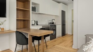 Une cuisine compacte avec une table et des chaises en bois, un lave-linge et un four encastré.