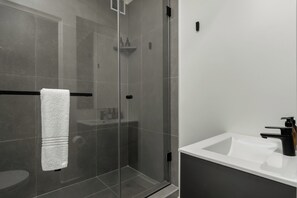 Bathroom features a glass-enclosed shower area with a white sink and black faucet.