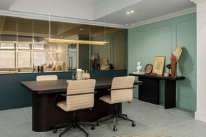 Conference room with a large mirror, dark table, and two comfortable chairs.
