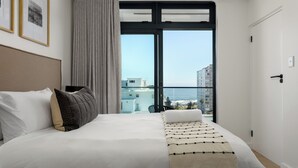 Une chambre d’hôtel moderne avec un grand lit, une vue sur la ville et un balcon.