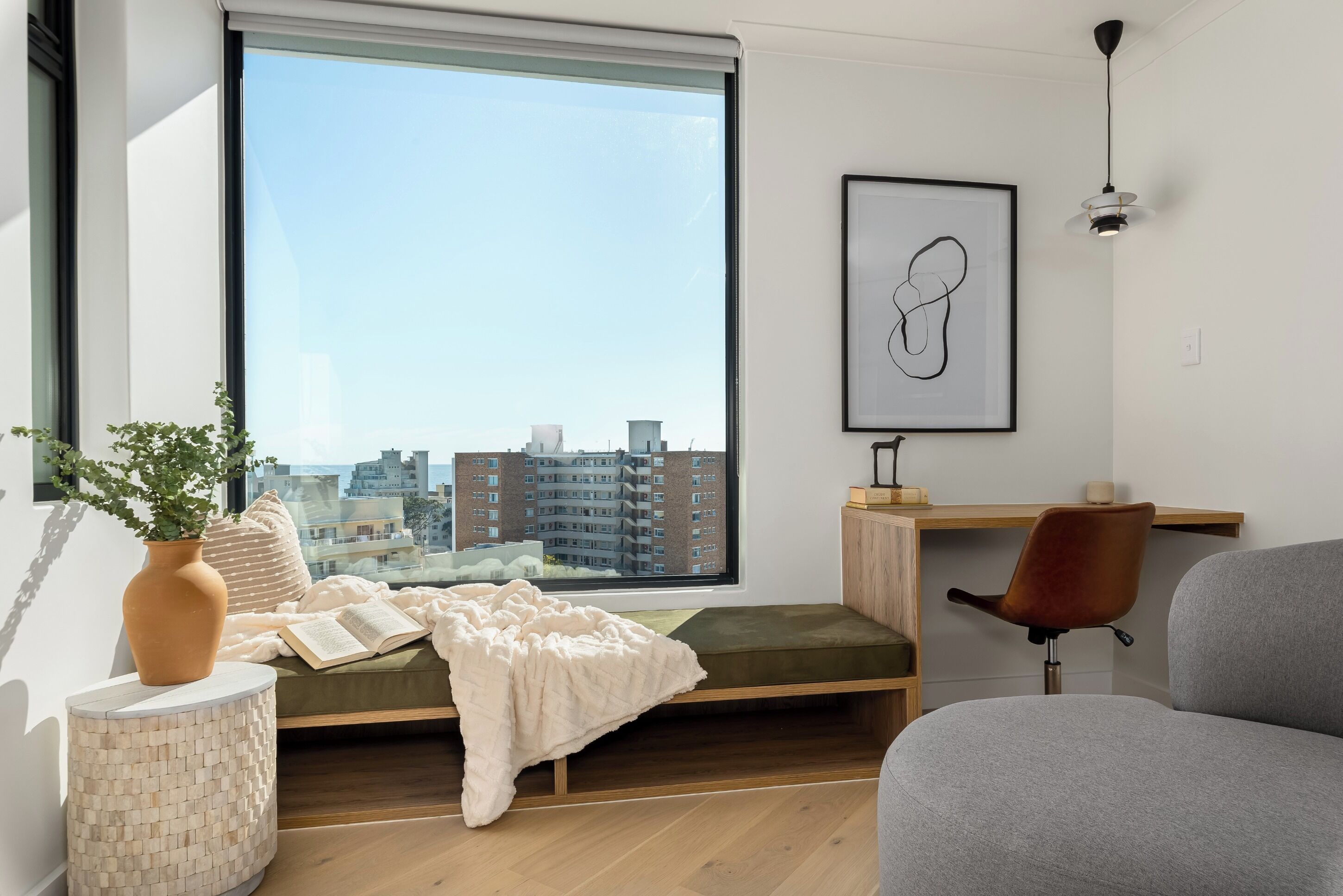 Een moderne slaapkamer met een groot raam, een bed met een groene matras, een nachtkastje met een vaas, een stoel en een bureau met een lamp.