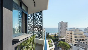Un balcon donnant sur la mer, une clôture décorée et une rangée de chaises vertes.