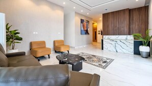 A modern lobby with leather sofas, a marble reception desk, and a large abstract painting on the wall. - De Castle hotels & Resort (Enugu)