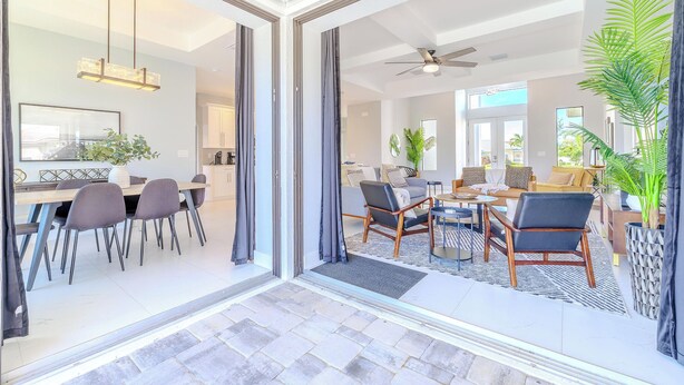 A modern open-plan living area with a dining area, a ceiling fan, and a large window providing natural light. - Sleeps 8 - Heated Pool - Games - Quiet area - Stars Vacation Rentals (Cape Coral)