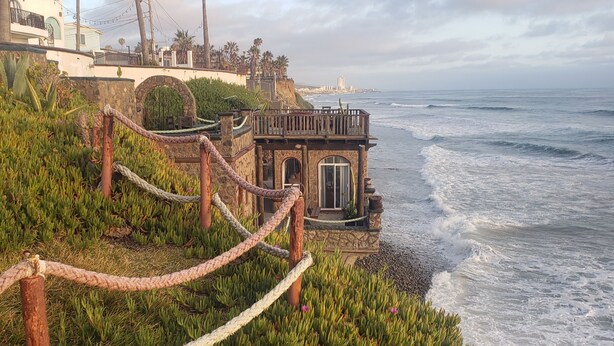Un edificio costiero con facciata in pietra, un piccolo ingresso e vista sull'oceano.