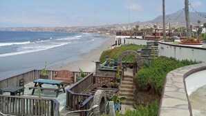 Una proprietà costiera con patio vista spiaggia, scalini in pietra e vista sull'oceano e sulle colline in lontananza.