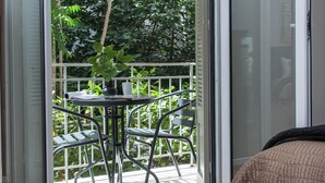 A room with a sliding glass door leading to an outdoor balcony with a table and chairs. - Fashionable Apt in Ano Kipseli w Balcony (Athens)