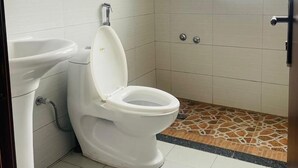 A small bathroom with a toilet, sink, and a window. - Goza Guest House (Addis Ababa)