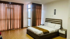 A bedroom with a wooden bed, a nightstand, and a window with curtains. - Goza Guest House (Addis Ababa)