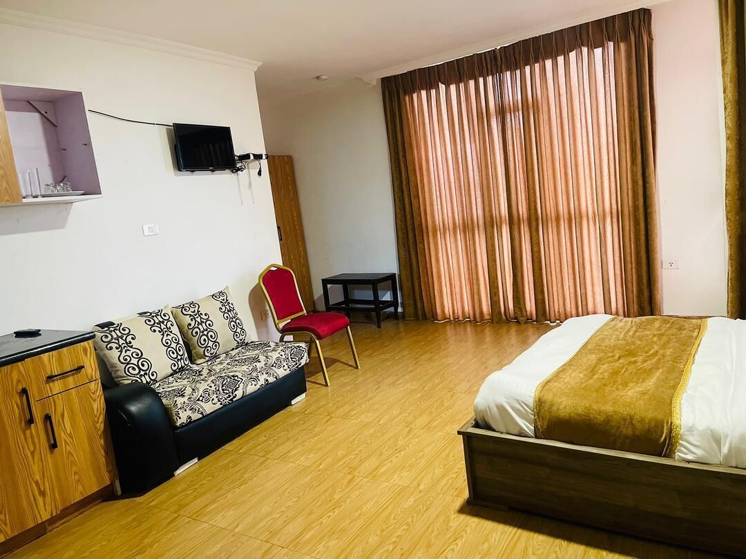 A hotel room with a bed, a sofa, a desk, and a chair.