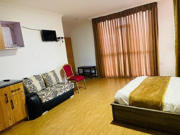 A hotel room with a bed, a sofa, a desk, and a chair.