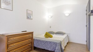 A bedroom with a bed, a wooden dresser, and two wall-mounted lights. - Chambre Saint Pierre - Hypercentre - Gaillac (Gaillac)