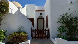 A white-walled building with a wooden gate, steps leading to a door with shutters, and a small number '3' sign. - Mojacar Beach 2 Bedroom House With sea View (Mojacar)