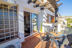 Een terras met een tafel en stoelen, een schuifdeur naar een kamer, en een Samsung airconditioner.