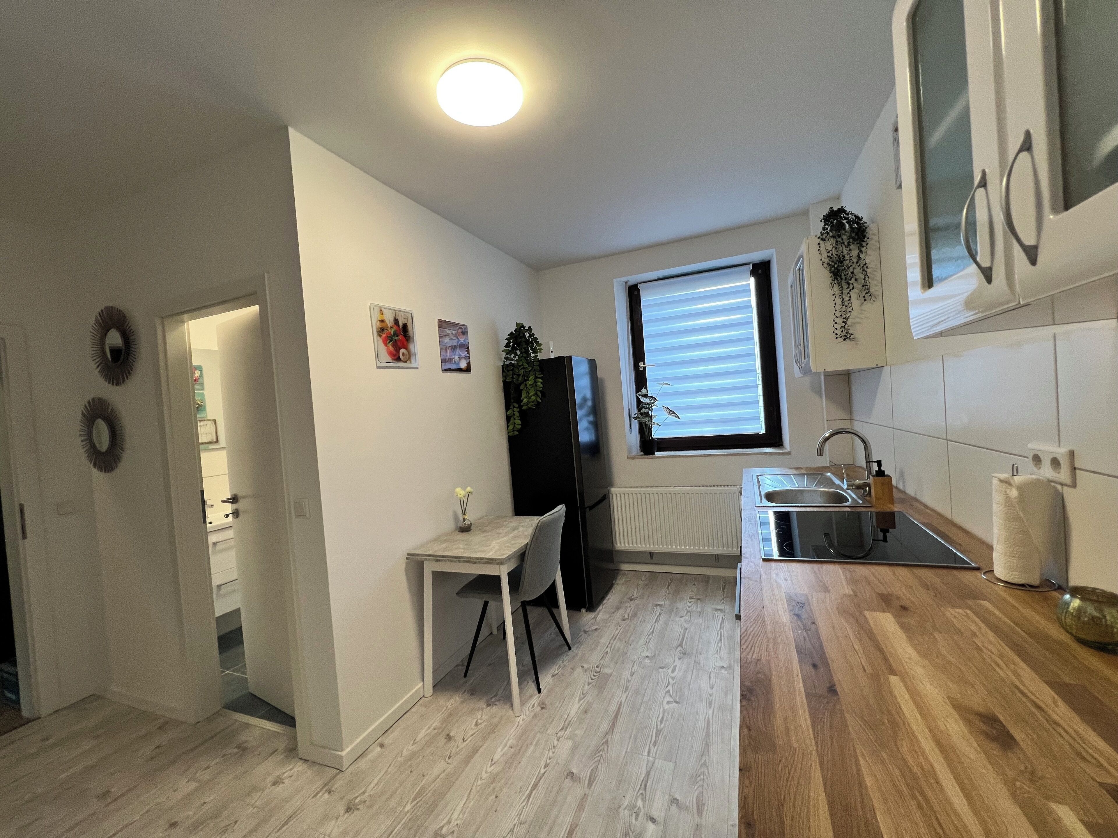 A small, well-lit kitchen with a window, a sink, and a countertop.