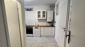 Un pasillo estrecho con suelo de madera que conduce a una zona de cocina.
