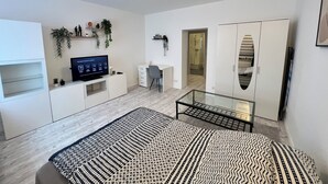 Un dormitorio moderno y bien iluminado con cama, escritorio y armario.