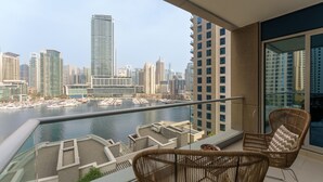 A balcony with wicker chairs and a view of a marina and city skyline.