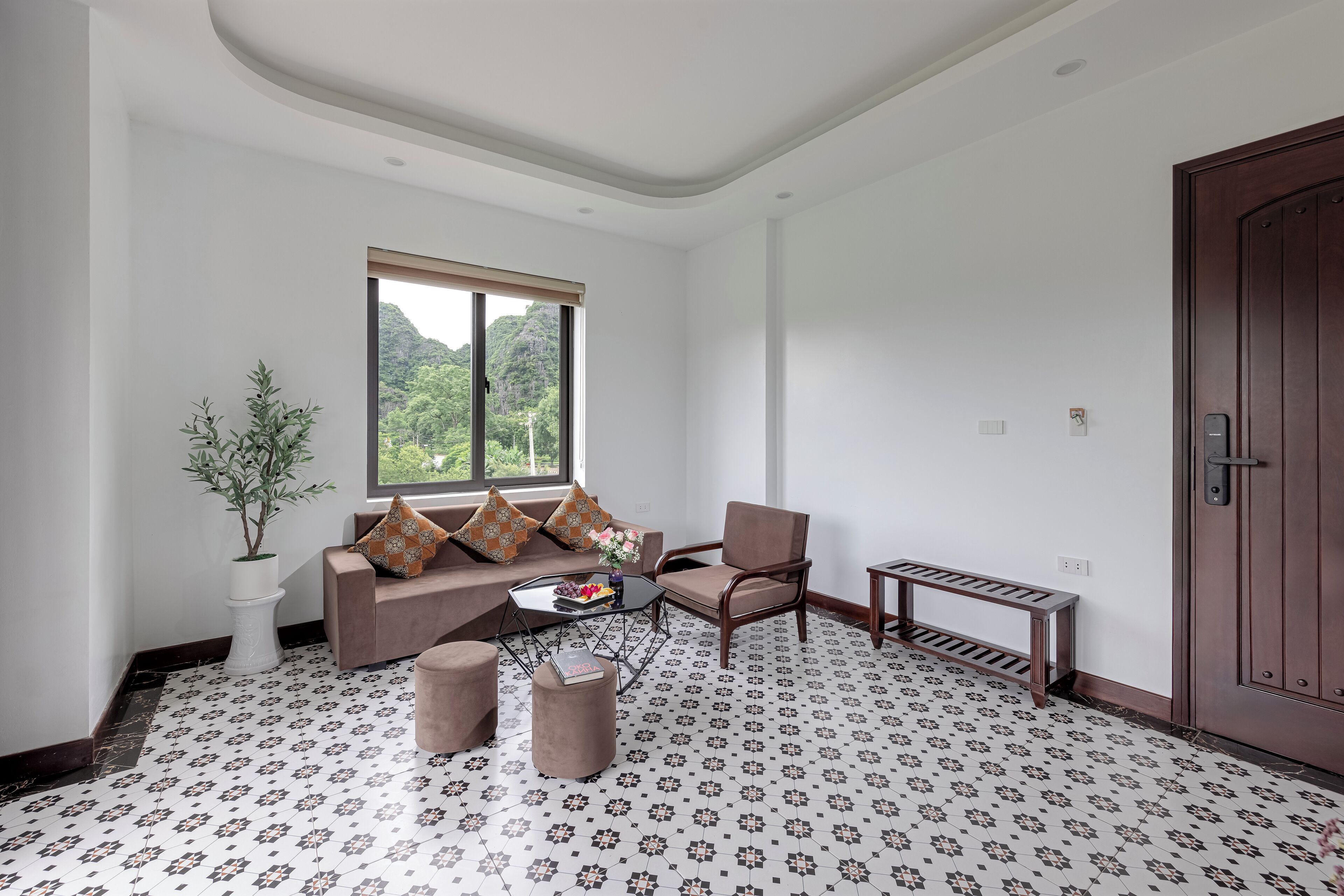A living room with a sofa, armchair, coffee table, and a potted plant.