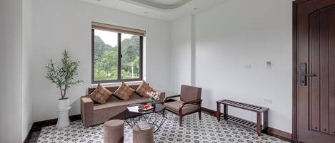 A living room with a sofa, armchair, coffee table, and a potted plant.