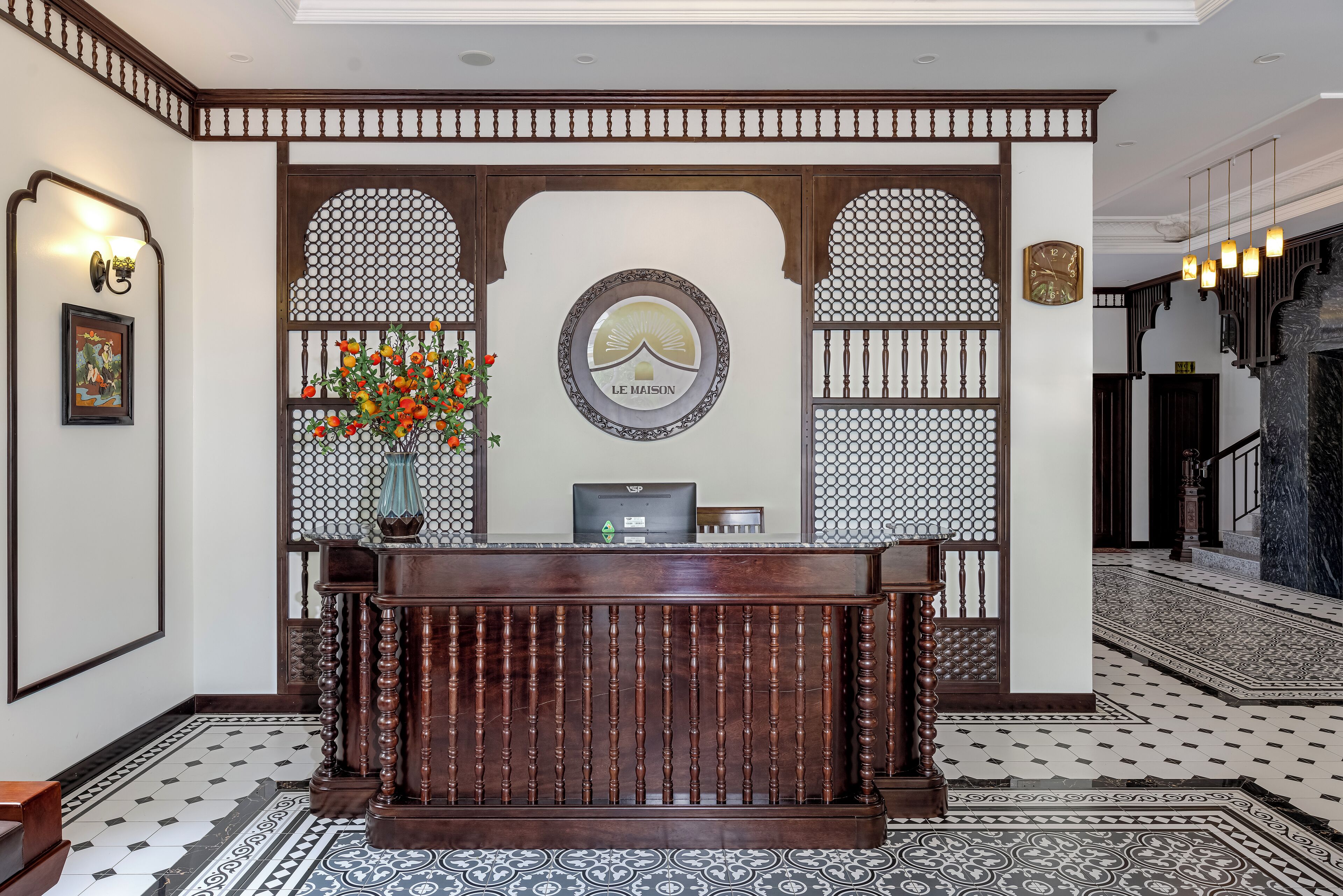 A reception desk with a logo, a clock, and a vase with flowers.