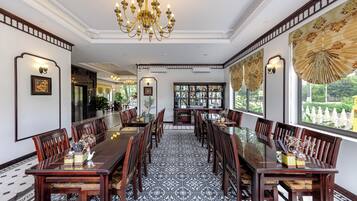 A formal dining room with a long table, chairs, and a chandelier.