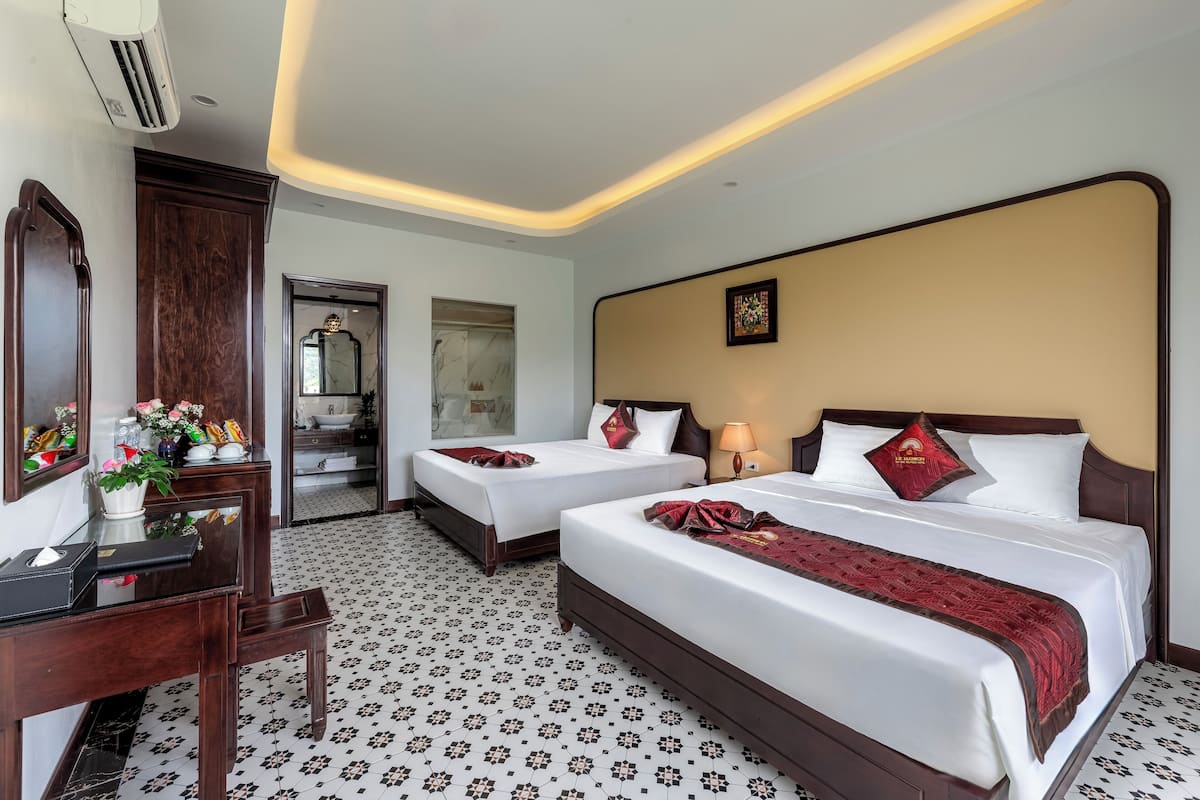 A hotel room with two beds, a desk, and a mirror.