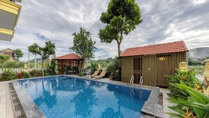A swimming pool with a tiled edge, surrounded by potted plants and a gazebo. - Le Maison Tam Coc Boutique Hotel (Nam Hoa Lu)