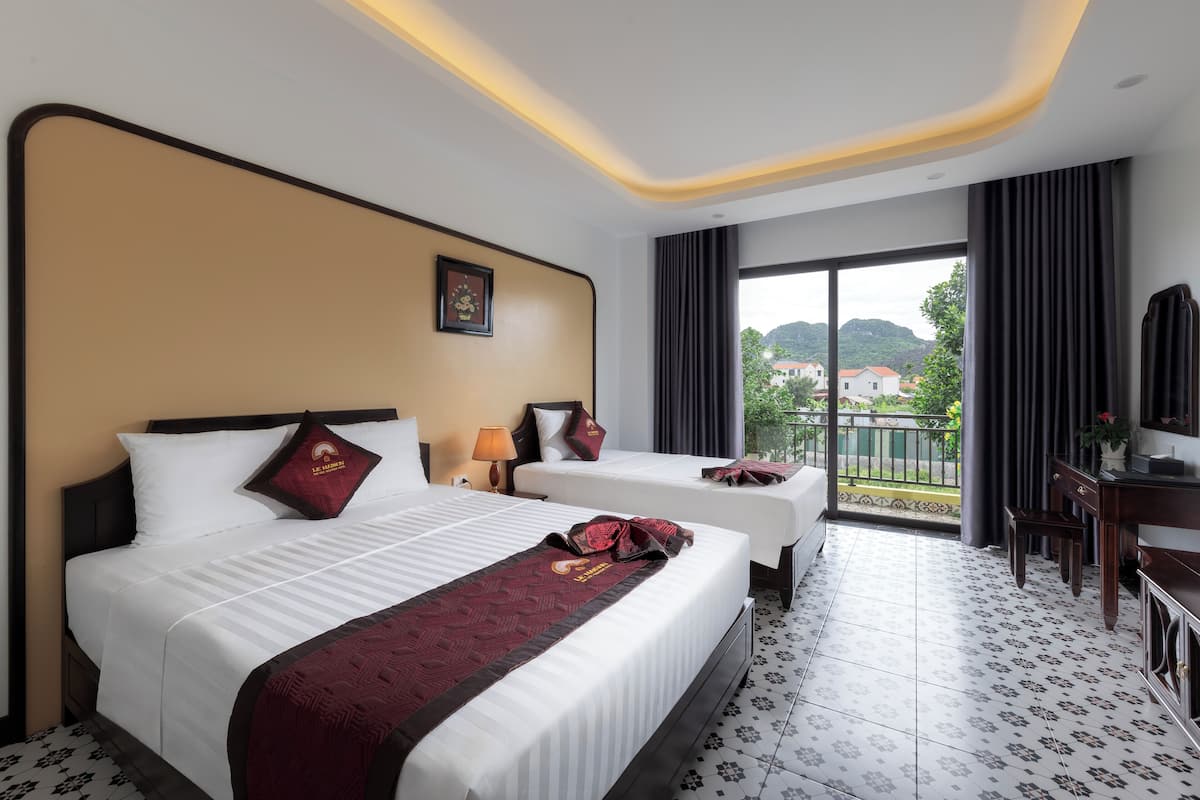 A hotel room with two beds, a balcony, and a view of the outside.
