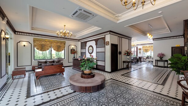 A spacious lobby with a central seating area, patterned flooring, and a decorative wall with a clock. - Le Maison Tam Coc Boutique Hotel (Nam Hoa Lu)