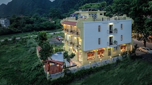 A multi-story hotel with a swimming pool, surrounded by lush greenery and mountains. - Le Maison Tam Coc Boutique Hotel (Nam Hoa Lu)