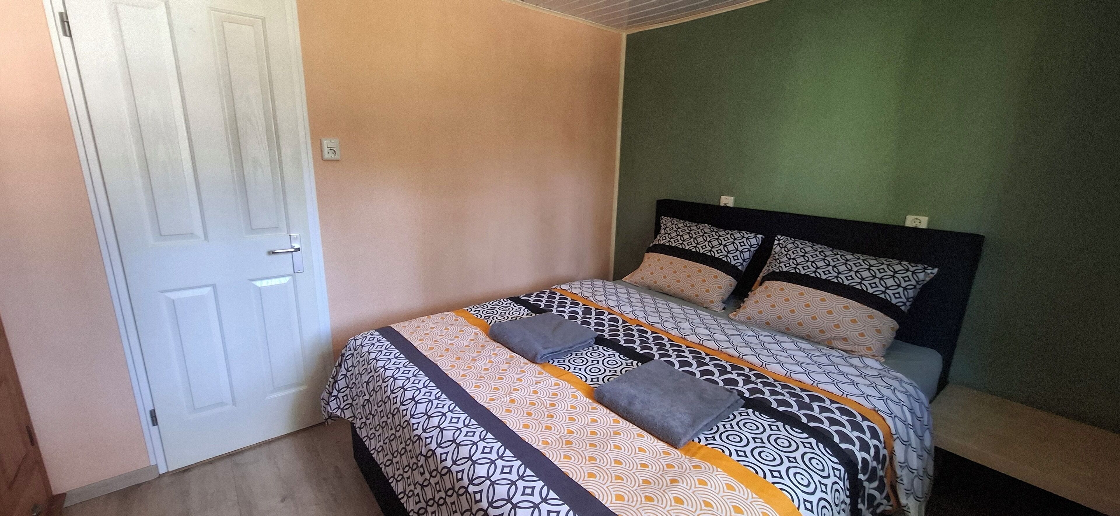 Een slaapkamer met een bed, een deur en een groene wand.
