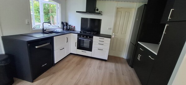 A modern kitchen with black and white cabinetry, a built-in oven, and a window providing natural light.