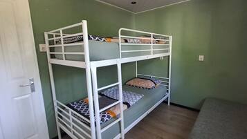 Een slaapkamer met een stapelbed, groene wanden, een witte deur en een grijze vloer.