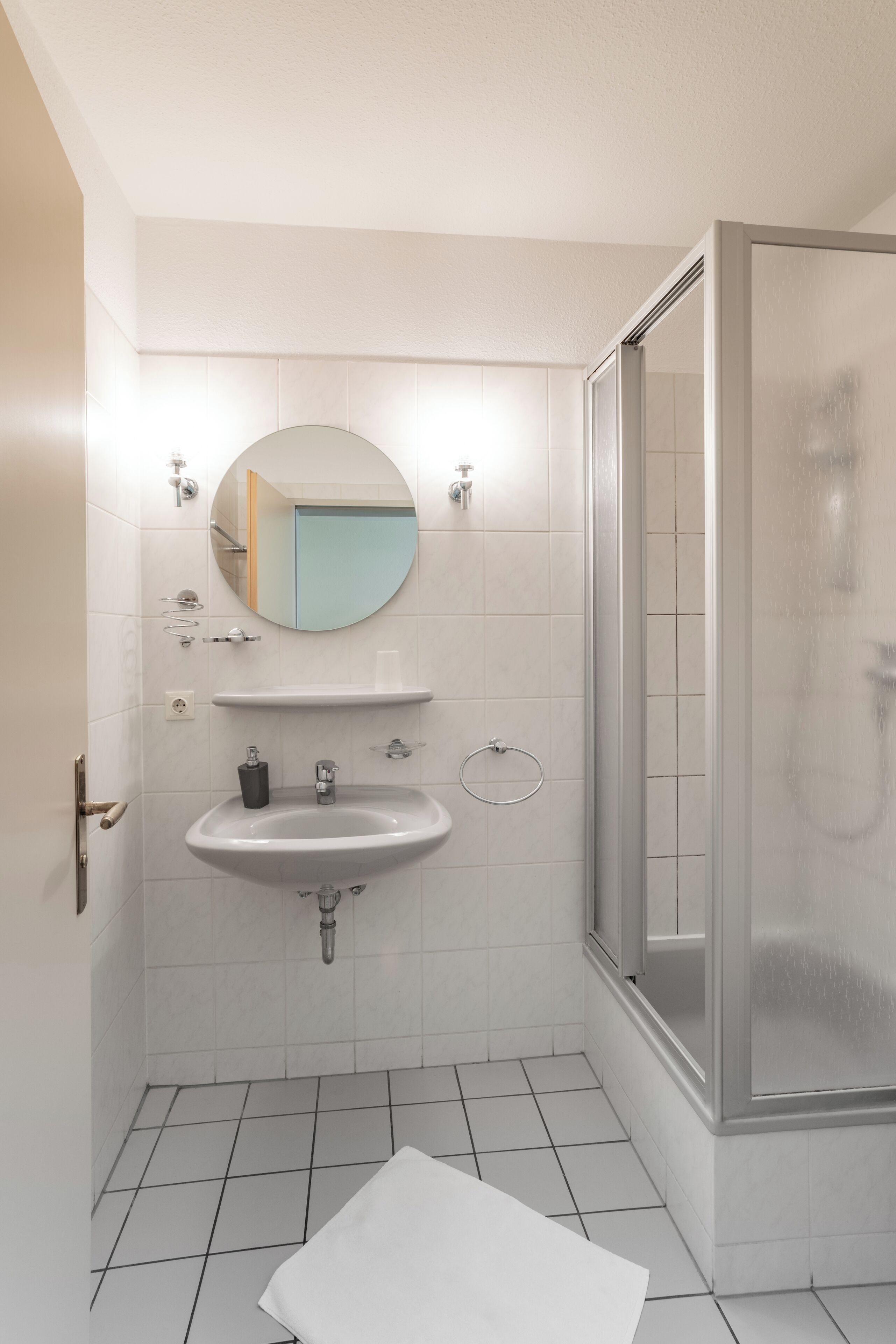 A modern bathroom with a white sink, mirror, and shower.