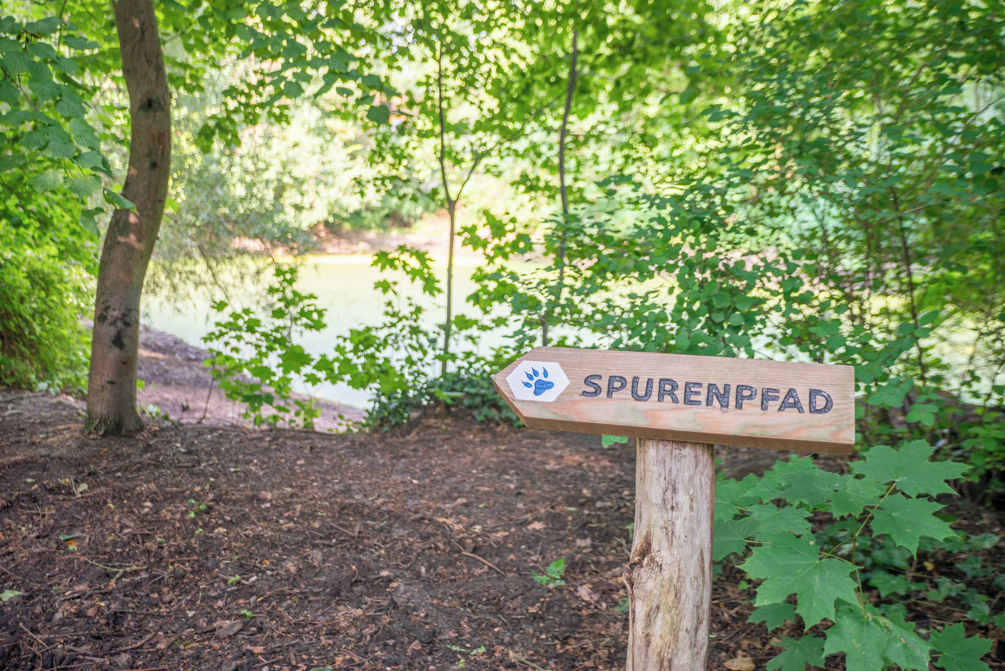 Een houten bord met de tekst 'SPURENFAD' en een pootafdruk symbool.