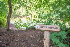 A wooden signpost with the text "SPURENFAD" and a paw print symbol. - Waldhotel Schöneiche - Self-Check-in (Schoeneiche bei Berlin)
