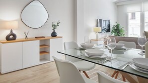 Een moderne eetruimte met een glazen tafel, witte stoelen en een minimalistisch ontwerp.