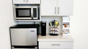 A modern kitchen with white cabinets, a stainless steel refrigerator, a microwave, and a coffee machine. - Cozy Studio Near Coral Gables (Miami)