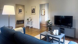 Una sala de estar moderna con sofá, televisor, lámpara y obras de arte en las paredes.