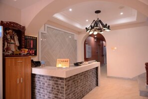 A reception area with a counter, a digital display, and a chandelier. - Qilong Hotel (Harbin Government Civil Aviation Building Shop) (Harbin)