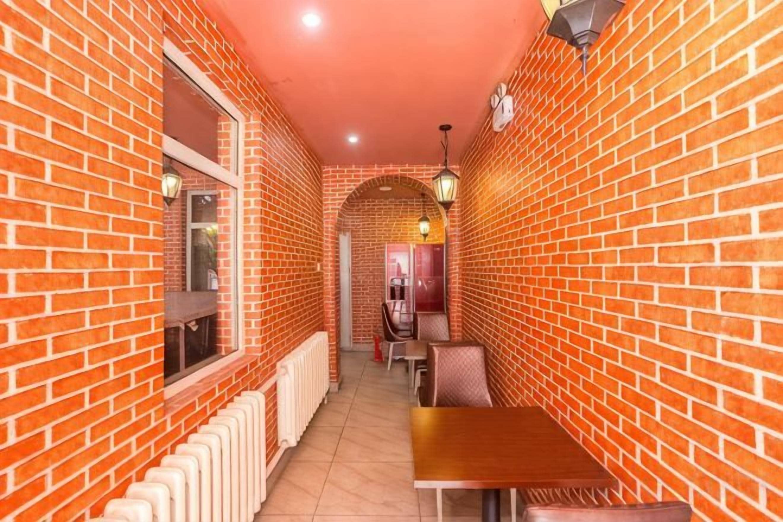 Un pasillo estrecho con paredes de ladrillo, un radiador y una mesa con sillas.