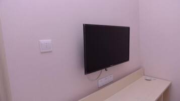 Un televisor montado en la pared, con un enchufe y un decodificador debajo.