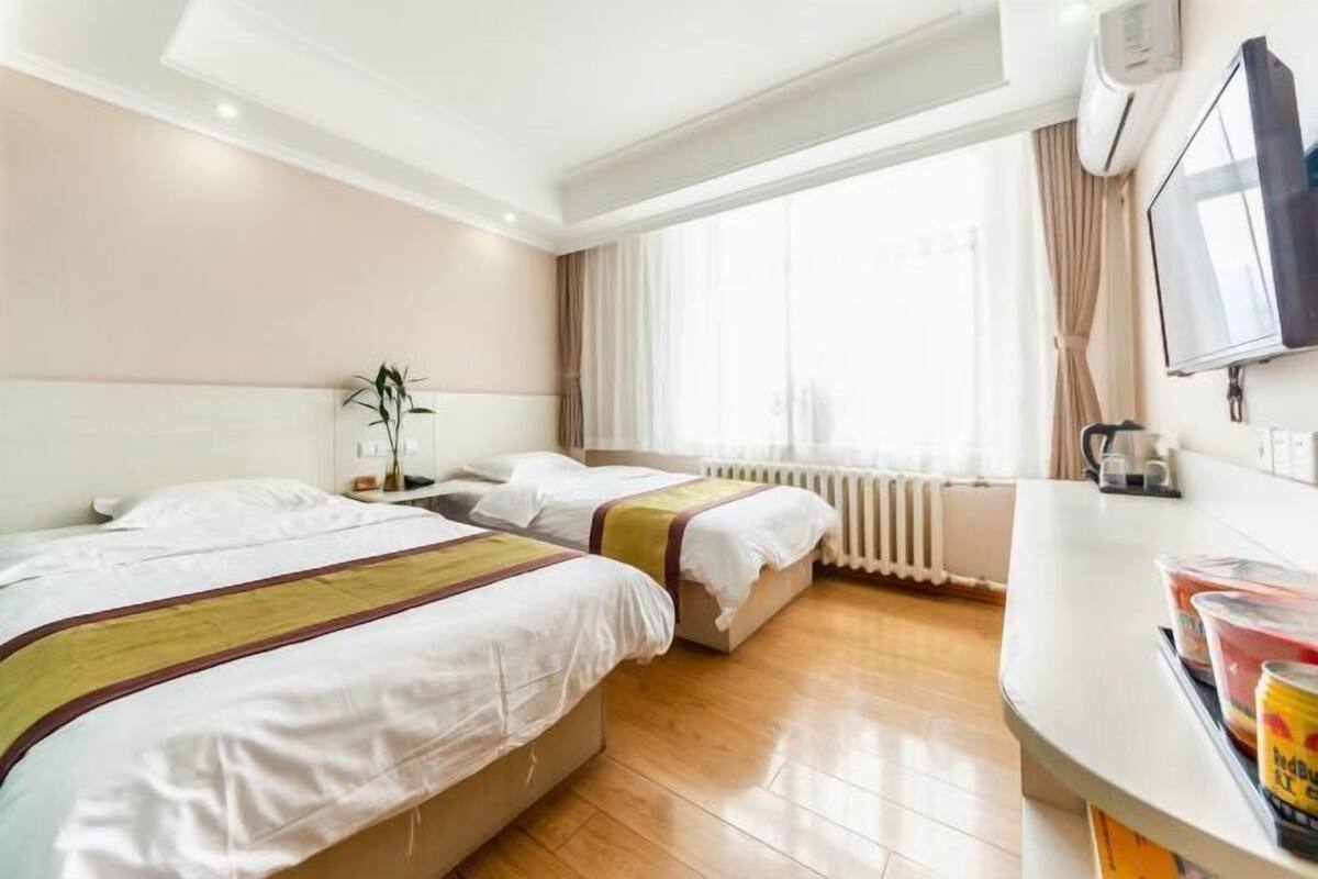 A hotel room with two beds, a large window, a flat-screen TV, and a minibar.