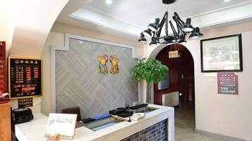 Una zona de recepción con mostrador, un menú digital, una obra de arte en la pared y un certificado enmarcado.