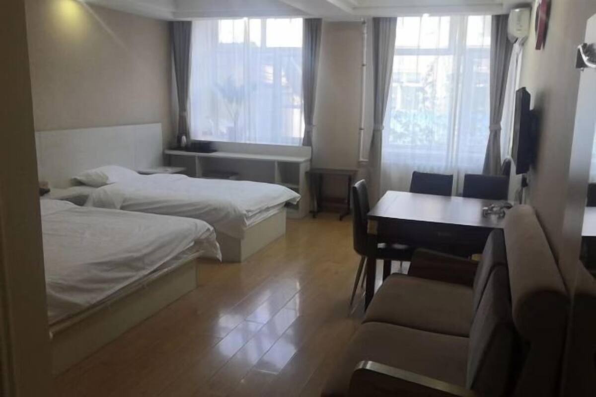 A hotel room with two beds, a dining table, and a sofa.