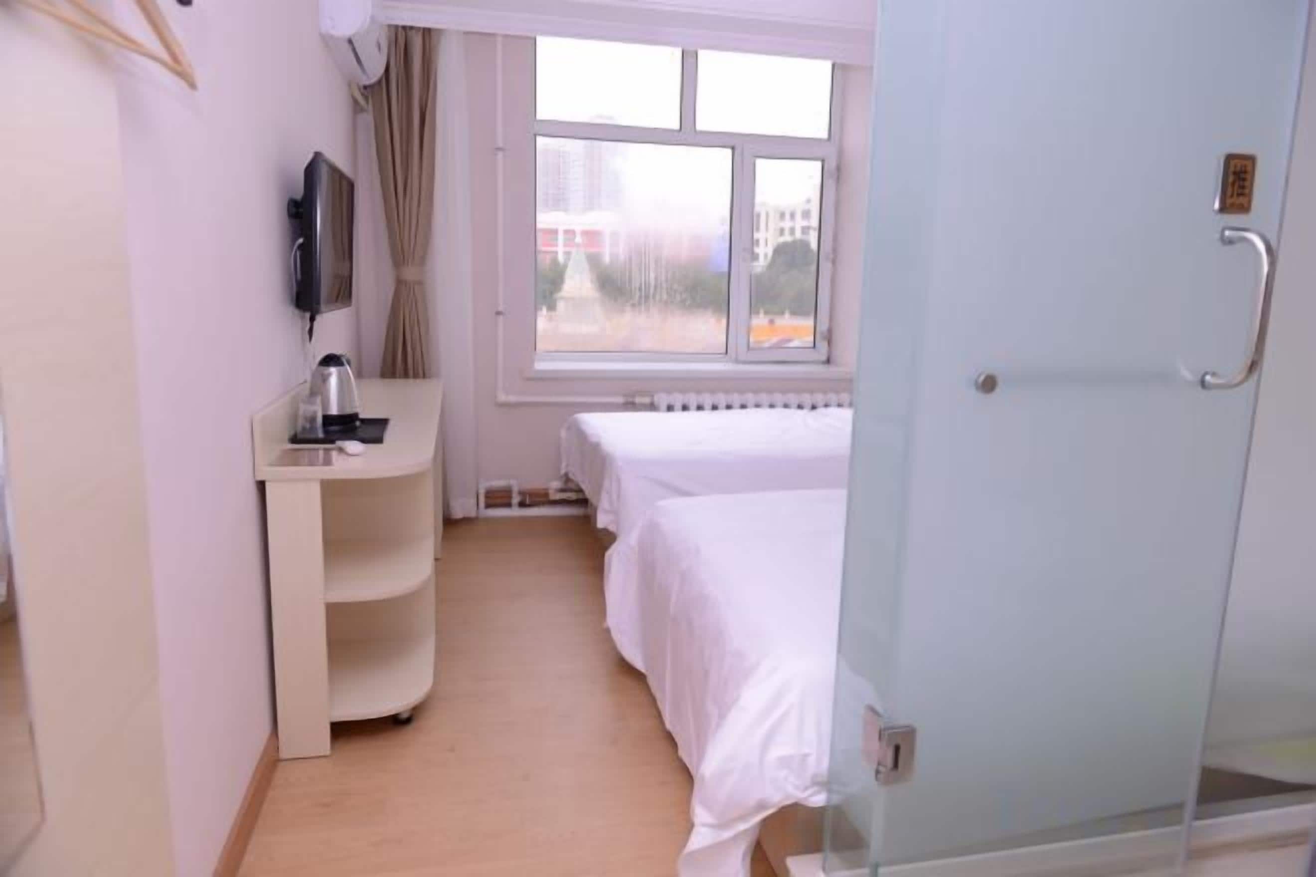 Una habitación de hotel con cama, escritorio, silla, ventana y puerta.
