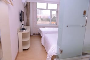 A hotel room with a bed, a desk with a chair, a window, and a door. - Qilong Hotel (Harbin Government Civil Aviation Building Shop) (Harbin)