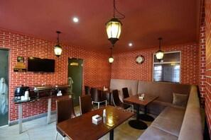 Un restaurant aux murs en briques, avec un bar, des tables et des chaises, et une horloge au mur.