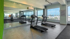A modern gym with treadmills, exercise equipment, and large windows offering city views. - Luxury, pool, gym in the city center (Distrito Nacional)